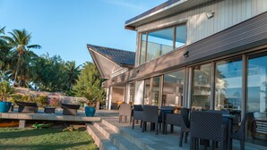A modern house with a patio area featuring outdoor furniture and a view of the surrounding landscape. - Villa Jessivia Beach (Moorea-Maiao)