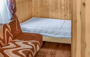 A small, wooden room with a single bed and a sofa.