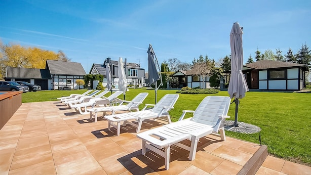 A patio with white lounge chairs and umbrellas, a pool, and a well-maintained lawn. - Beautiful home in Postomino (Postomino)
