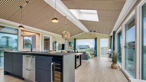 Een moderne keuken met een centraal eiland, een eetgedeelte met uitzicht en een ruime woonkamer met balkon.