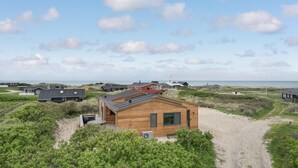 Een kustbezit met meerdere huizen, een zandpad en uitzicht op zee.