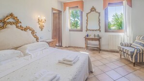 Une chambre d’hôtel avec un grand lit, une petite table, une chaise et un miroir.