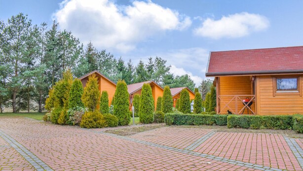 A row of wooden cabins with a paved walkway in front. - 2 bedroom awesome home in Jaroslawiec (Jaroslawiec)