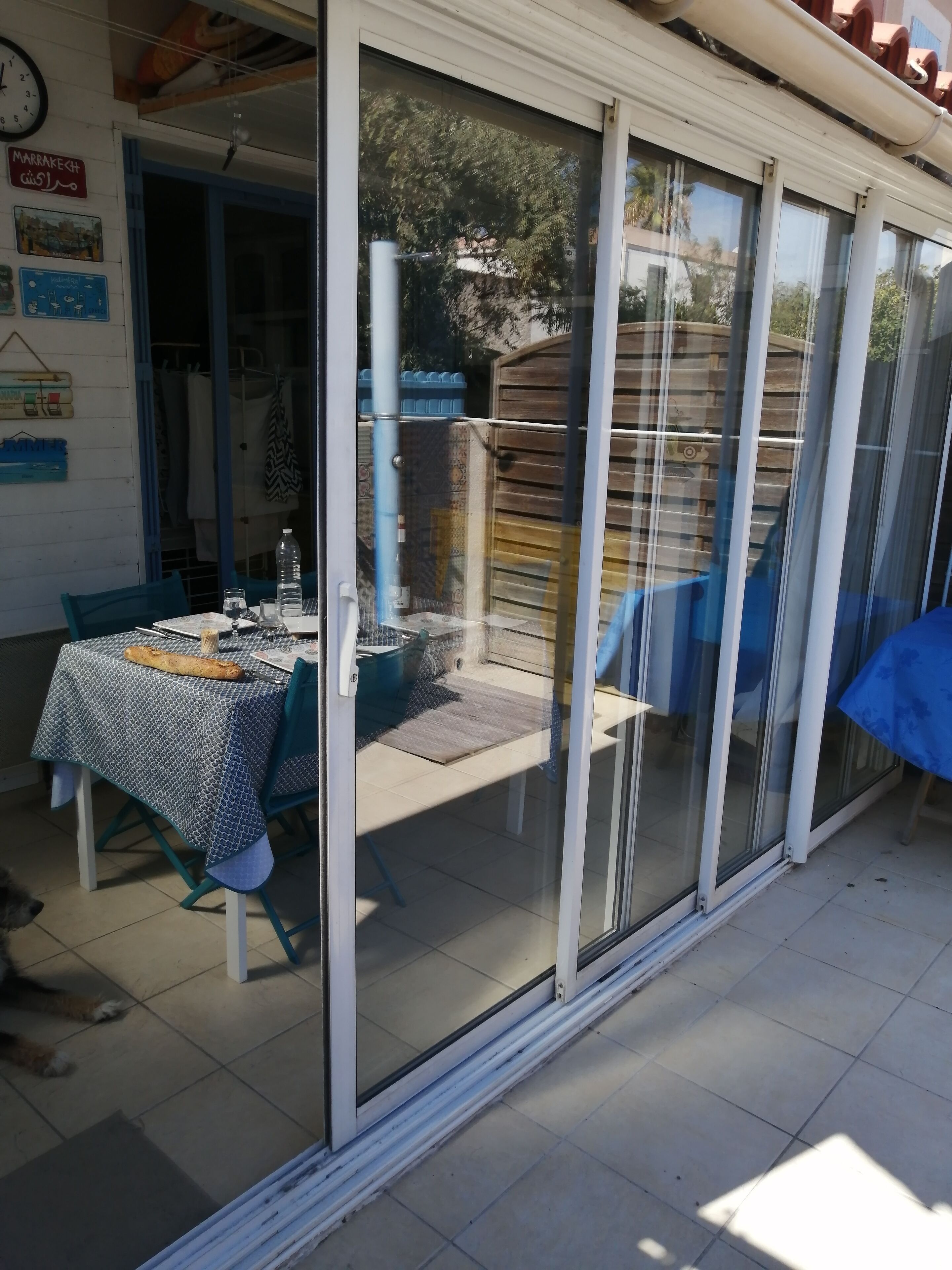 A patio area with a table set for dining, a sliding glass door leading to a covered outdoor space, and a clock on the wall.