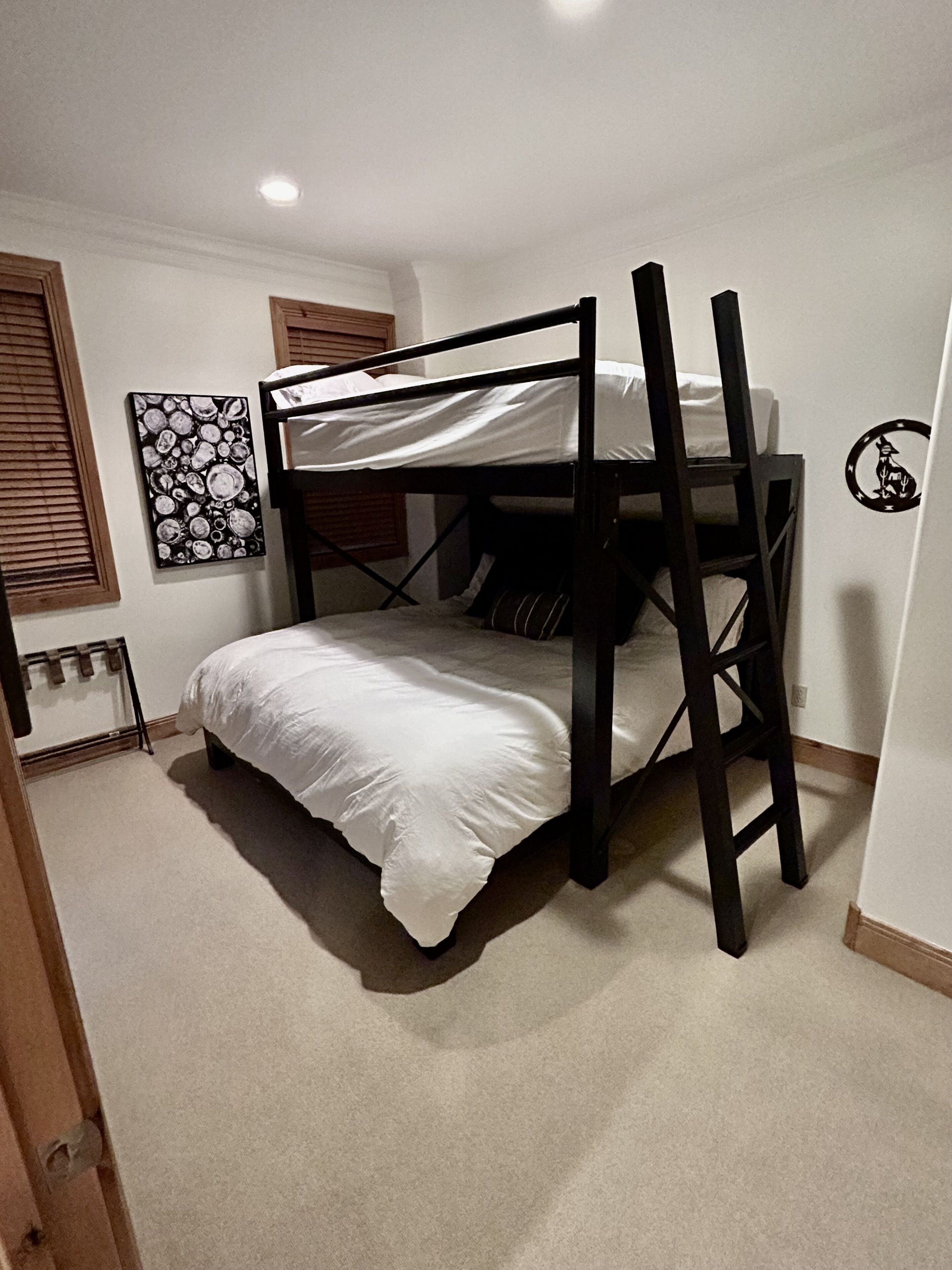 A bunk bed in a room with a ceiling light, a wall art piece, and a small emblem on the wall.