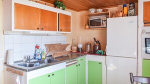 A compact kitchen with wooden cabinets, a microwave, a refrigerator, and a sink. - 2 bedroom beautiful home in Söderåkra (Söderåkra)