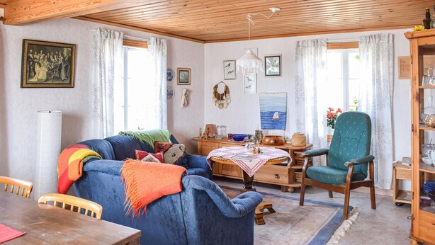 A cozy living room with a blue sofa, a wooden dining table, and a green armchair. - 2 bedroom beautiful home in Söderåkra (Söderåkra)