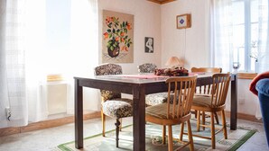 A dining area with a wooden table and chairs, a painting on the wall, and a window with curtains. - 2 bedroom beautiful home in Söderåkra (Söderåkra)