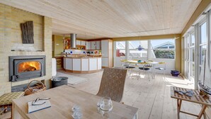 Une cuisine moderne dotée d’un îlot central, d’une cheminée et d’un coin repas offrant une vue sur l’extérieur.