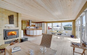Cozy living space with a central kitchen, fireplace, and dining area, offering a view of the surrounding area.