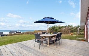 A wooden deck with a round table and four chairs, an umbrella, and a bottle of wine. - Awesome home in Slagelse with WiFi (Slagelse)