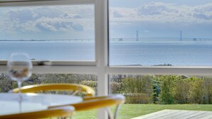 Une vue depuis une fenêtre donnant sur une étendue d’eau, avec un pont visible au loin.