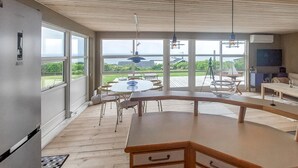 Une cuisine moderne dotée de grandes fenêtres, d’une table à manger ronde et offrant une vue sur l’extérieur.
