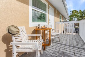 A wooden deck with white furniture, including a table and chairs, and a white fence in the background. - Beach, pool & fun times @ the Blue Lagoon! (Fort Myers Beach)