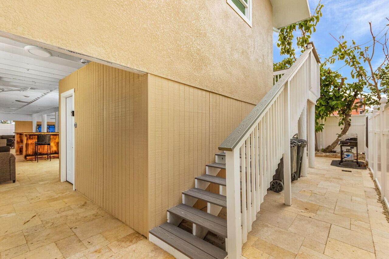 A staircase leading to a covered outdoor area with a wooden floor and a white railing.