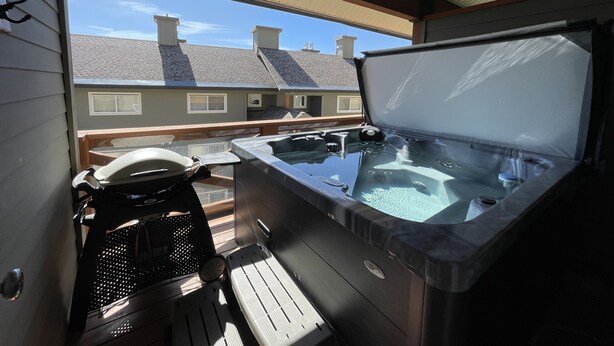 Un jacuzzi en un balcón con vista despejada a casas vecinas.
