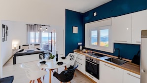Una cucina compatta con zona pranzo, vista mare e balcone con divano.