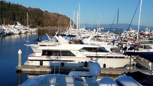 Un puerto deportivo con varios yates amarrados, cielo despejado y un paisaje montañoso al fondo.
