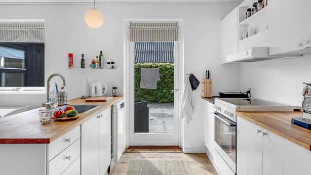 A modern kitchen with white cabinetry, a wooden countertop, a built-in oven, and a hanging light fixture. - Beautiful home in Svaneke with WiFi (Svaneke)