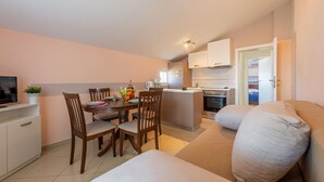 Un espace de vie compact comprenant un coin repas, une kitchenette et une chambre.