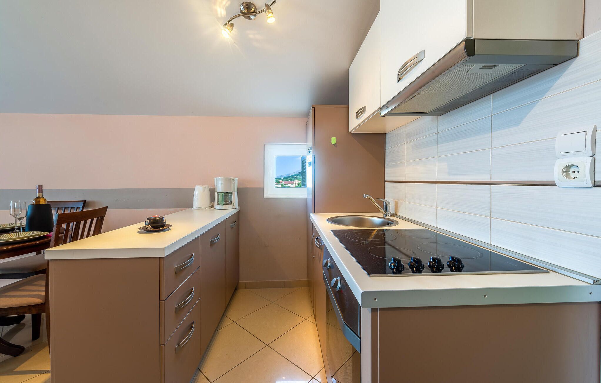 Una cocina moderna con una isla central, horno empotrado y ventana con vistas.