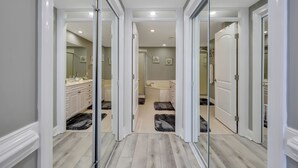 A hallway leading to a bathroom with a sink, mirror, and toilet. - The SandPiper  - Ocean Front Condo (Tybee Island)