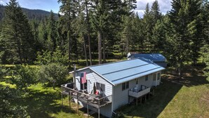 Eine Hütte mit blauem Dach, einer Veranda mit Sitzgelegenheit und einer US-amerikanischen Flagge.