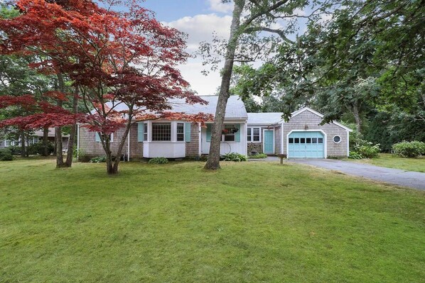 Une maison à deux étages avec un porche à l’avant, un garage et une pelouse bien entretenue.