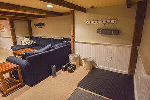 Un espacio de sala acogedor con un sofá azul oscuro, una pequeña mesa de madera y un par de mancuernas.