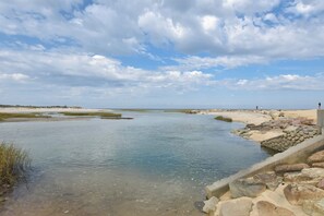 Un paisaje costero con cielo despejado, agua tranquila y terreno rocoso.