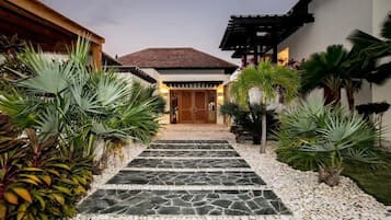 Stroll along the pathway lined with lush tropical plants to a charming building with a traditional architectural style.