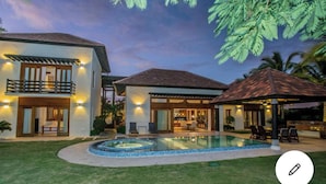 Une maison à deux étages avec une piscine, un patio couvert et un espace extérieur bien éclairé.