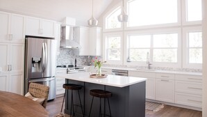 A modern kitchen with white cabinetry, stainless steel appliances, and a large island with bar stools.