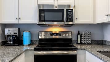 Enjoy cooking in this well-equipped kitchen with a microwave oven, stovetop, coffee maker, and granite countertops.