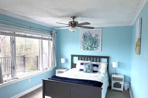 A bedroom with a bed, a ceiling fan, a window with blinds, and a painting on the wall. - Spacious House for Beach Getaway - Outdoor Shower -Beach Pass Included! (Charlestown)