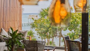 An outdoor seating area with wicker chairs and tables, overlooking the sea.