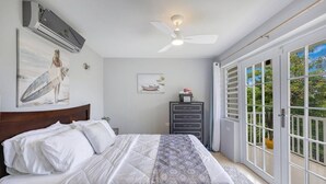 A bedroom with a bed, a ceiling fan, an air conditioning unit, a dresser, and a sliding glass door leading to a balcony. - Soak up breathtaking sunsets from any of our three private balconies!
 (Rincon)