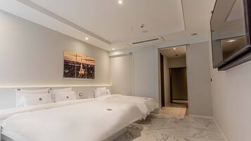 A modern hotel room with a large bed, a flat-screen TV, and a cityscape artwork on the wall.