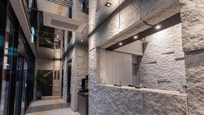 Eine moderne Lobby mit Steinwand, einer Rezeption und einer Treppe.