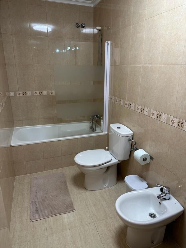 A bathroom with a bathtub, toilet, bidet, and a shower.