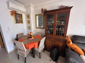 A dining area with a round table, chairs, a cabinet with glass doors, and a sofa.