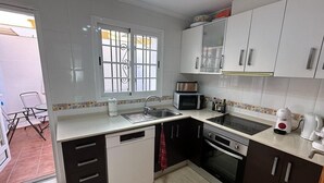 Una cucina con mobili bianchi e marrone scuro, un forno a microonde, un fornello e un lavello.