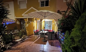 An outdoor patio area with a table and chairs, a fan, and a decorative umbrella.