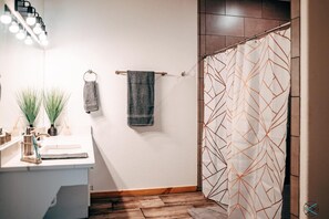 Bathroom features a sink, mirror, and geometric patterned shower curtain.