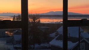 A view through a window of a snowy landscape with houses and a sunset. - Uptown in Downtown (Anchorage)