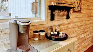Een gezellige kamer met een koffieapparaat, kopjes en een dienblad met toevoegingen.