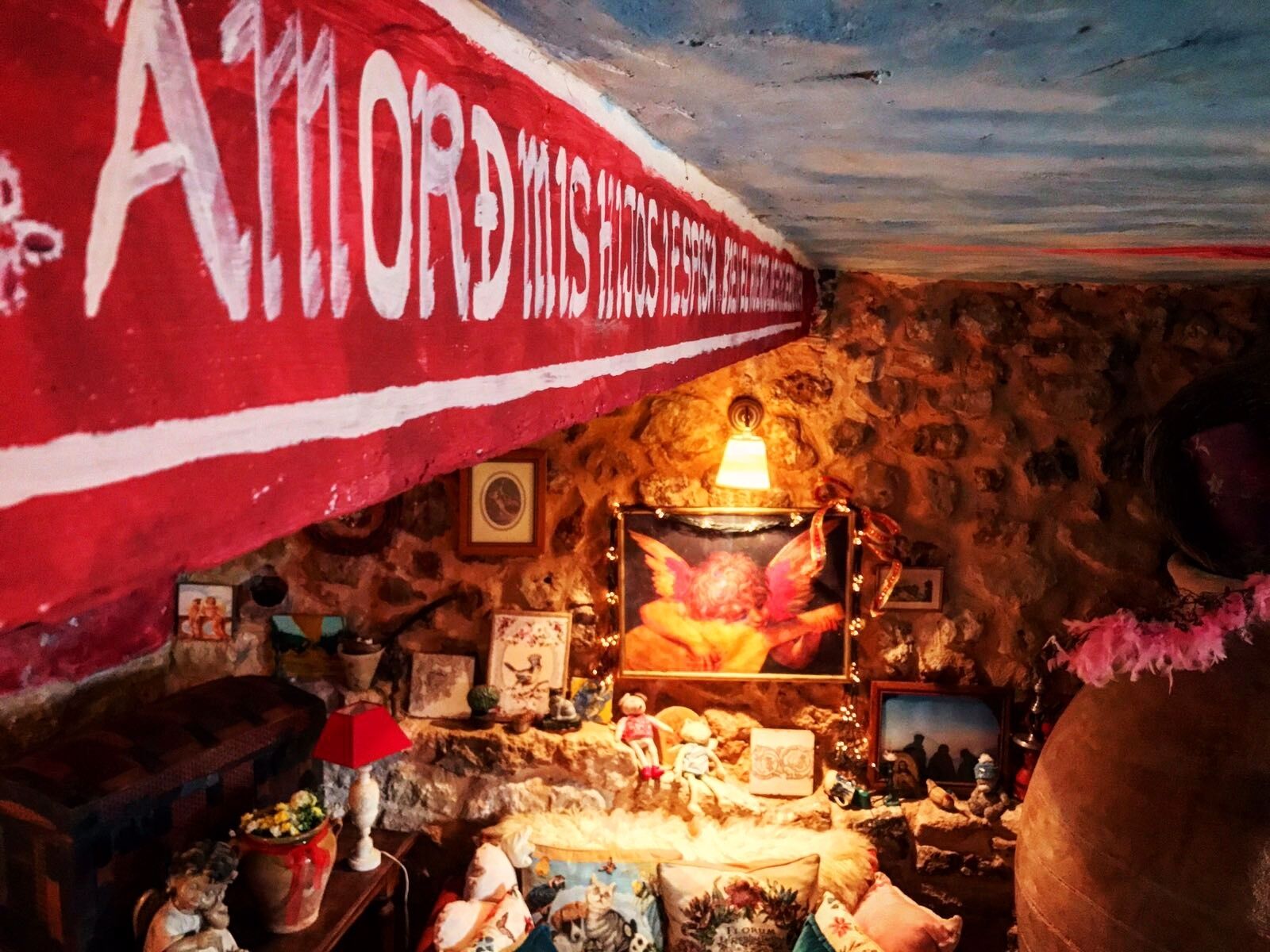 A room with a stone wall, a red banner, and various decorations including a lamp, a framed picture, and a globe.