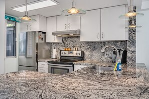 A modern kitchen with granite countertops, stainless steel appliances, and pendant lighting.