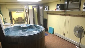 Une pièce dotée d’un jacuzzi, d’un ventilateur sur pied et d’un sol carrelé.