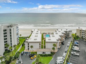Un hotel con piscina en la azotea, junto a una playa.